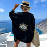 Aisling eye-catching blouse, an oversized button-up with lightweight crinkled texture and shimmering sequin-and-bead evil-eye motif on the back; relaxed drop-shoulder fit in black or white, ideal as a beach coverup or for casual chic layers.