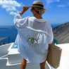 Aisling eye-catching blouse, an oversized button-up with lightweight crinkled texture and shimmering sequin-and-bead evil-eye motif on the back; relaxed drop-shoulder fit in black or white, ideal as a beach coverup or for casual chic layers.