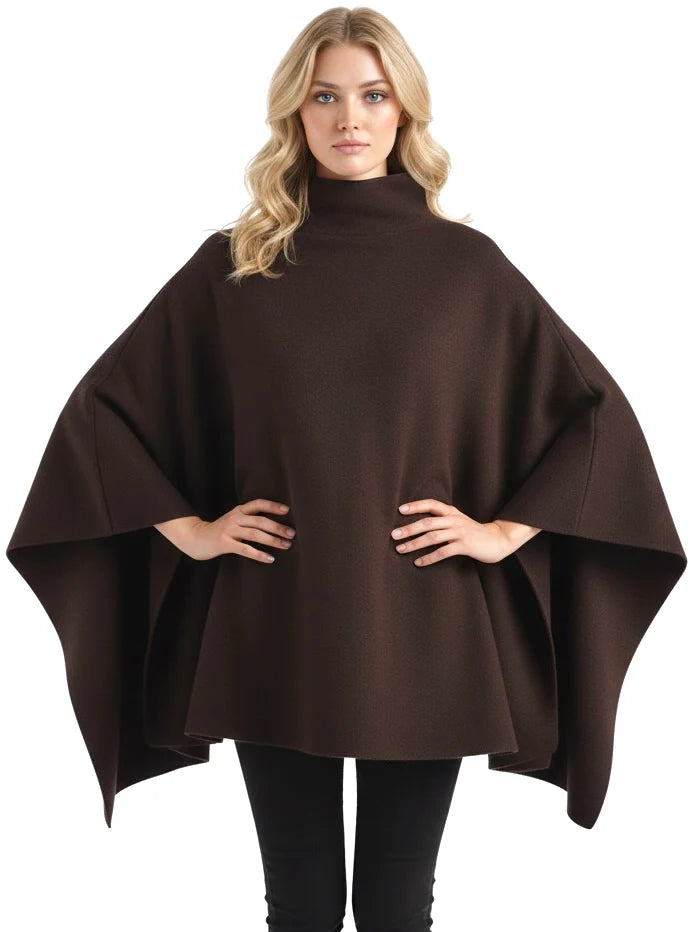 Alannah dark brown knit poncho cape featuring a refined high neckline and fluid, side-draped silhouette. Soft, medium-weight knit provides cozy warmth and effortless layering over jeans, tailored trousers or dresses for elevated everyday looks.