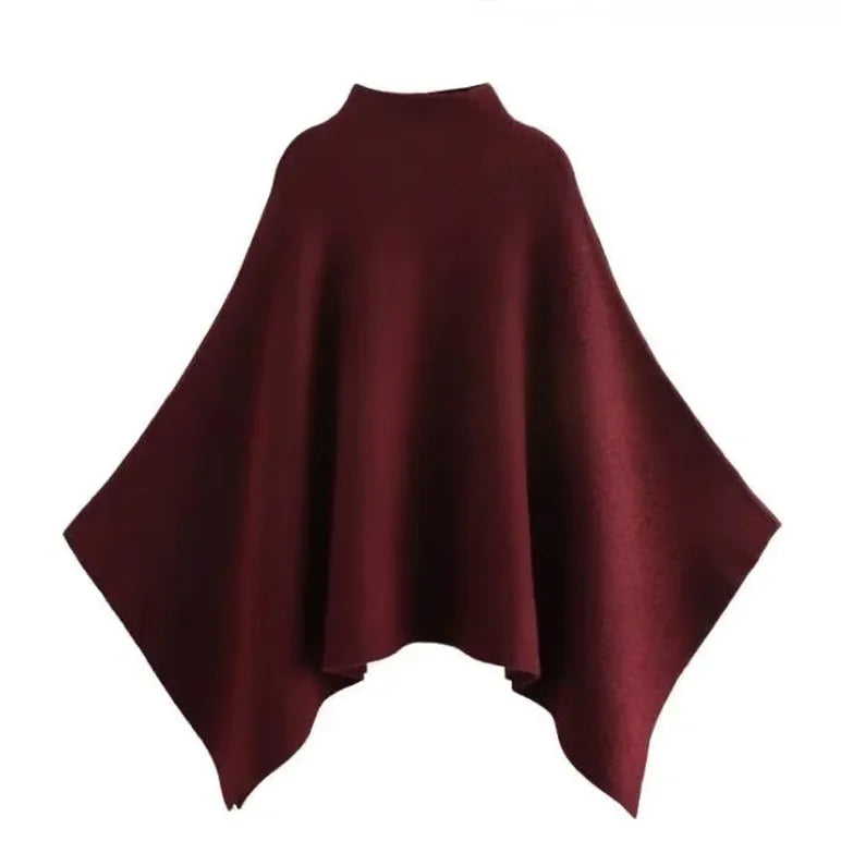 Alannah dark brown knit poncho cape featuring a refined high neckline and fluid, side-draped silhouette. Soft, medium-weight knit provides cozy warmth and effortless layering over jeans, tailored trousers or dresses for elevated everyday looks.