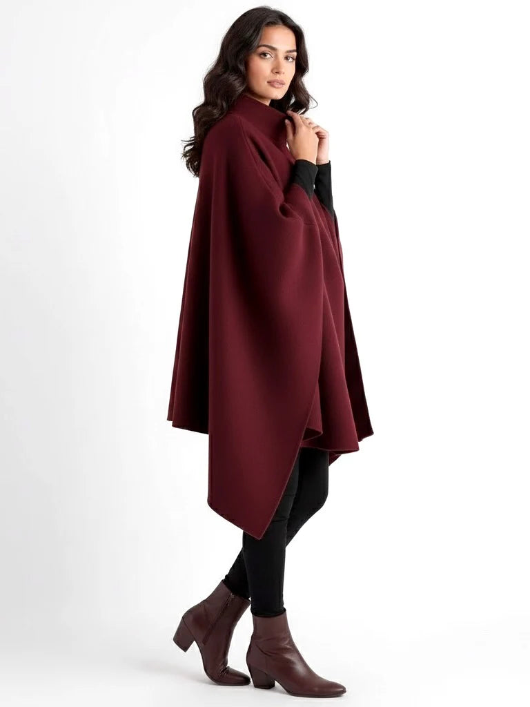 Alannah dark brown knit poncho cape featuring a refined high neckline and fluid, side-draped silhouette. Soft, medium-weight knit provides cozy warmth and effortless layering over jeans, tailored trousers or dresses for elevated everyday looks.
