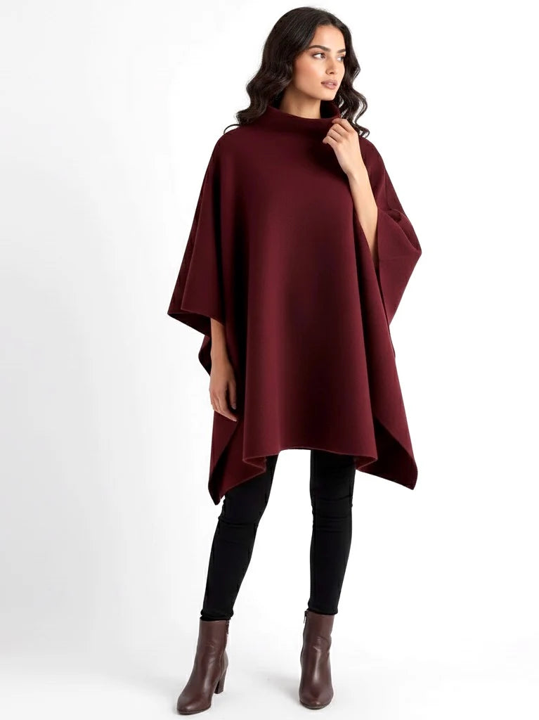 Alannah dark brown knit poncho cape featuring a refined high neckline and fluid, side-draped silhouette. Soft, medium-weight knit provides cozy warmth and effortless layering over jeans, tailored trousers or dresses for elevated everyday looks.