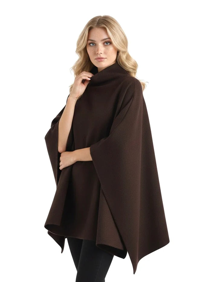Alannah dark brown knit poncho cape featuring a refined high neckline and fluid, side-draped silhouette. Soft, medium-weight knit provides cozy warmth and effortless layering over jeans, tailored trousers or dresses for elevated everyday looks.