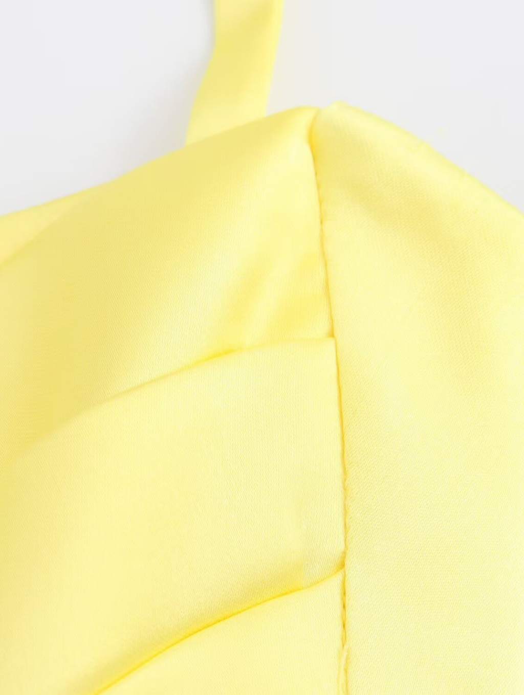 Amalfi Satin Mini Dress in lemon yellow with structured pleated bandeau bodice, adjustable thin straps, open back with criss-cross ties and a flared double-layered skirt. Polyester satin offers fluid movement for parties, vacations and seaside events.