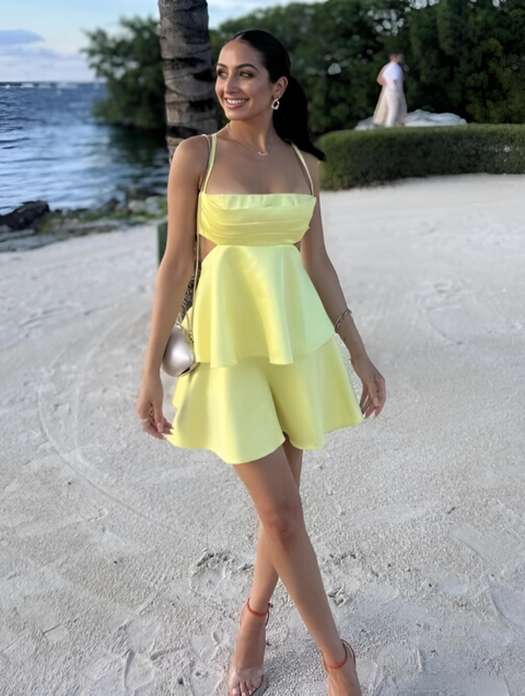 Amalfi Satin Mini Dress in lemon yellow with structured pleated bandeau bodice, adjustable thin straps, open back with criss-cross ties and a flared double-layered skirt. Polyester satin offers fluid movement for parties, vacations and seaside events.