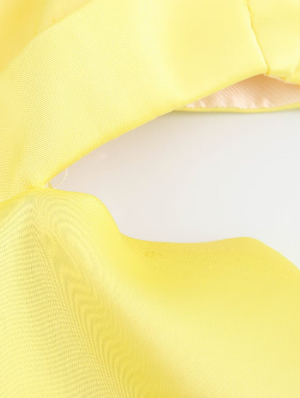 Amalfi Satin Mini Dress in lemon yellow with structured pleated bandeau bodice, adjustable thin straps, open back with criss-cross ties and a flared double-layered skirt. Polyester satin offers fluid movement for parties, vacations and seaside events.