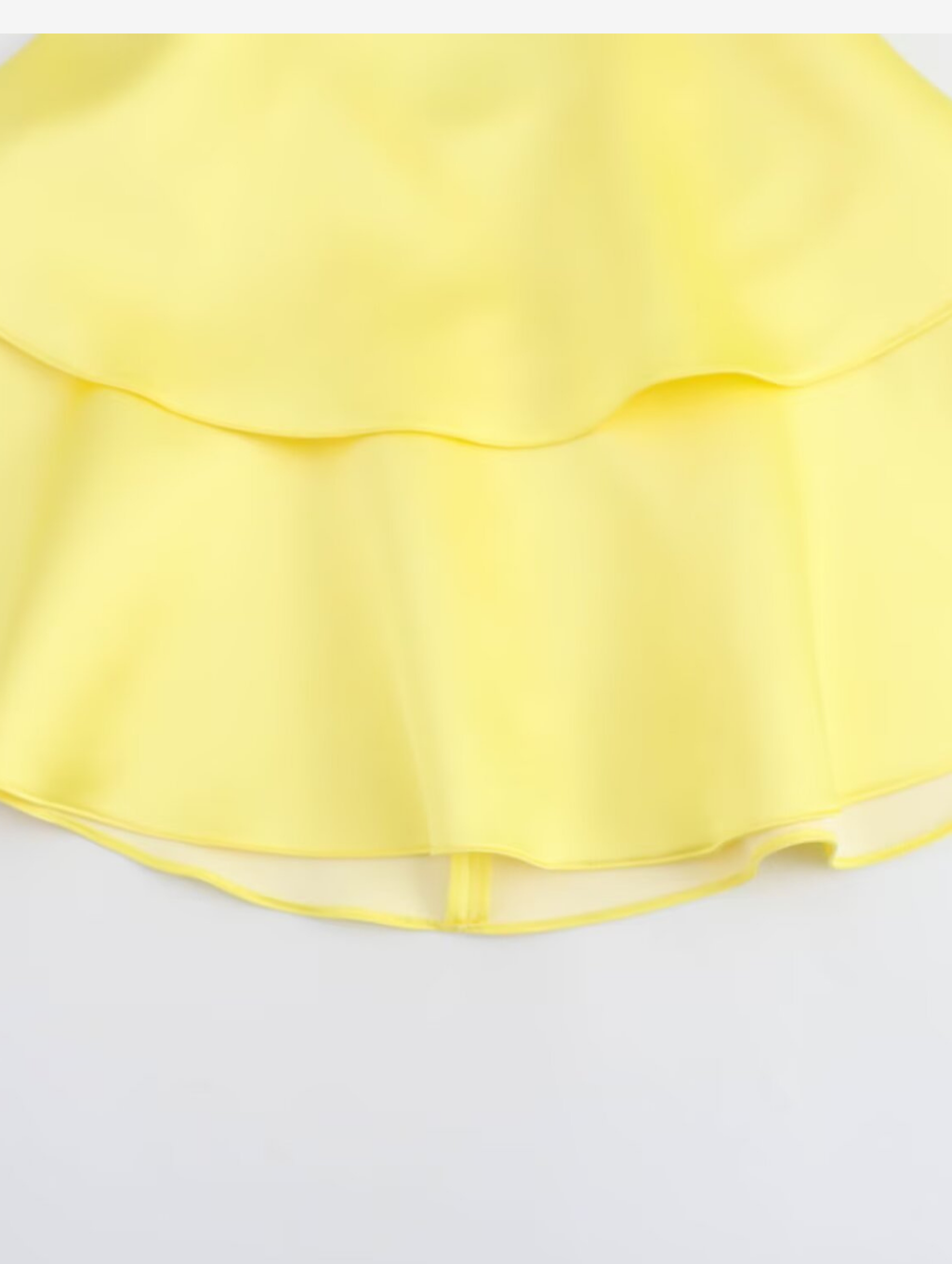 Amalfi Satin Mini Dress in lemon yellow with structured pleated bandeau bodice, adjustable thin straps, open back with criss-cross ties and a flared double-layered skirt. Polyester satin offers fluid movement for parties, vacations and seaside events.