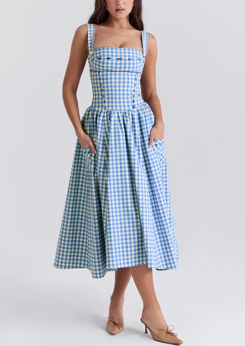 Ariana Sleeveless Midi Sundress in blue-cream gingham with a square neckline, wide straps and a fitted bodice trimmed with ribbon eyelets. Gathered midi skirt with side patch pockets and back zipper; chic and versatile for daytime events.