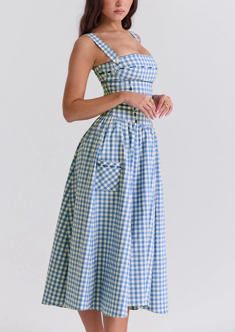 Ariana Sleeveless Midi Sundress in blue-cream gingham with a square neckline, wide straps and a fitted bodice trimmed with ribbon eyelets. Gathered midi skirt with side patch pockets and back zipper; chic and versatile for daytime events.