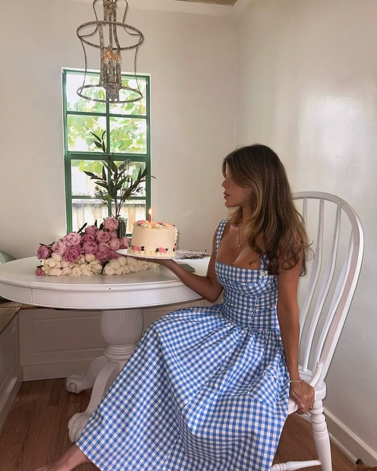 Ariana Sleeveless Midi Sundress in blue-cream gingham with a square neckline, wide straps and a fitted bodice trimmed with ribbon eyelets. Gathered midi skirt with side patch pockets and back zipper; chic and versatile for daytime events.
