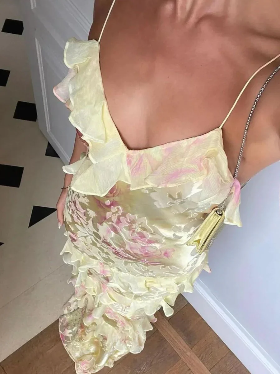 Maxi dress with delicate straps and cascading ruffle tiers, featuring a soft floral pattern and a graceful V neckline; lightweight, fluid drape creates feminine movement, ideal for garden parties, weddings, evening dinners or elegant daytime events.