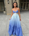 Catarina ombré cutout maxi dress blending sky blue to deep cobalt, featuring a soft triangle bust with front knot, side waist cutouts, adjustable spaghetti straps, and a high-waisted gathered tiered skirt in lightweight polyester with a subtle sheen.