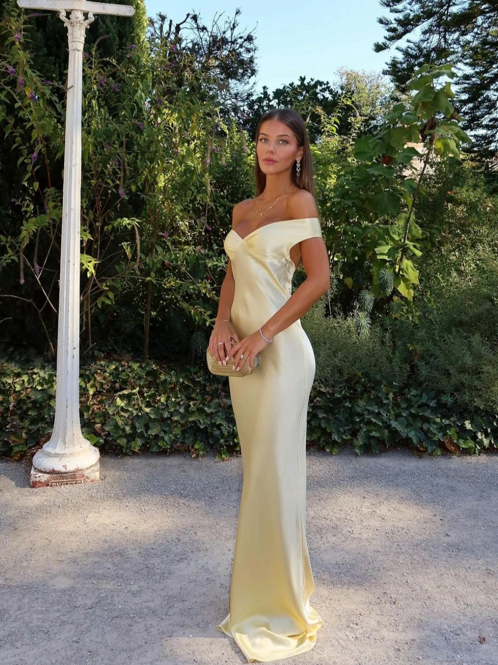 Emory satin backless maxi dress featuring an off-shoulder band, soft twist at the bust, and a sleek, body-skimming silhouette that falls to the floor. Lightweight satin with a refined sheen—ideal for weddings, formal dinners, and elegant evening events.
