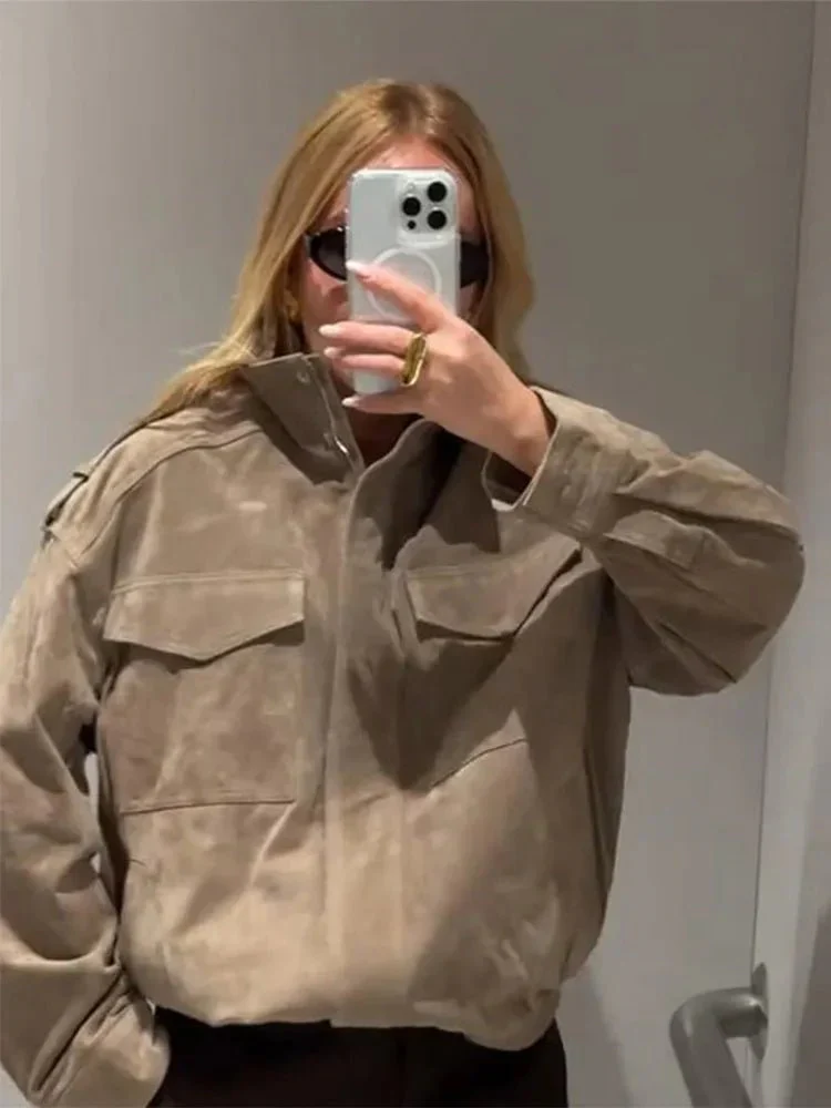 Women’s cropped moto jacket in beige, made from suede-like fabric with a lapel collar, shoulder epaulets and large front pockets. Softly structured silhouette layers over knits or tees, adding a refined, vintage-utility touch for cool-weather styling.