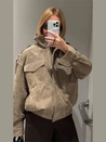 Women’s cropped moto jacket in beige, made from suede-like fabric with a lapel collar, shoulder epaulets and large front pockets. Softly structured silhouette layers over knits or tees, adding a refined, vintage-utility touch for cool-weather styling.