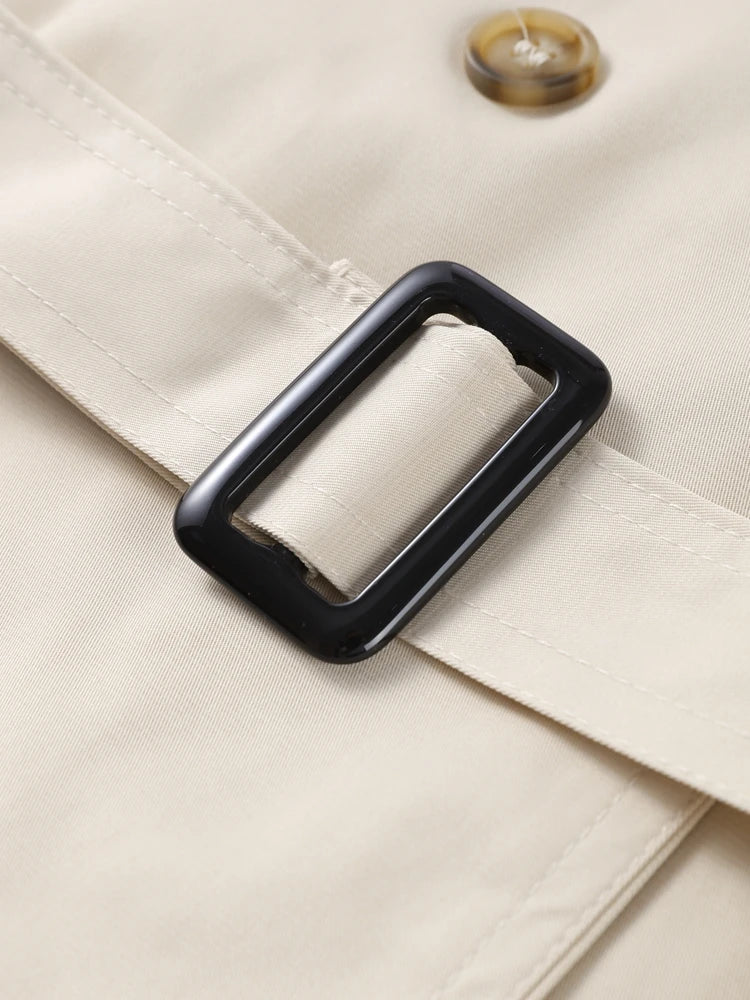 Isabelle high-neck belted trench coat in premium cotton blend with structured stand collar, double-breasted buttons, epaulettes and adjustable cuffs. Tailored silhouette layers over dresses, denim or trousers for refined autumn-winter style.