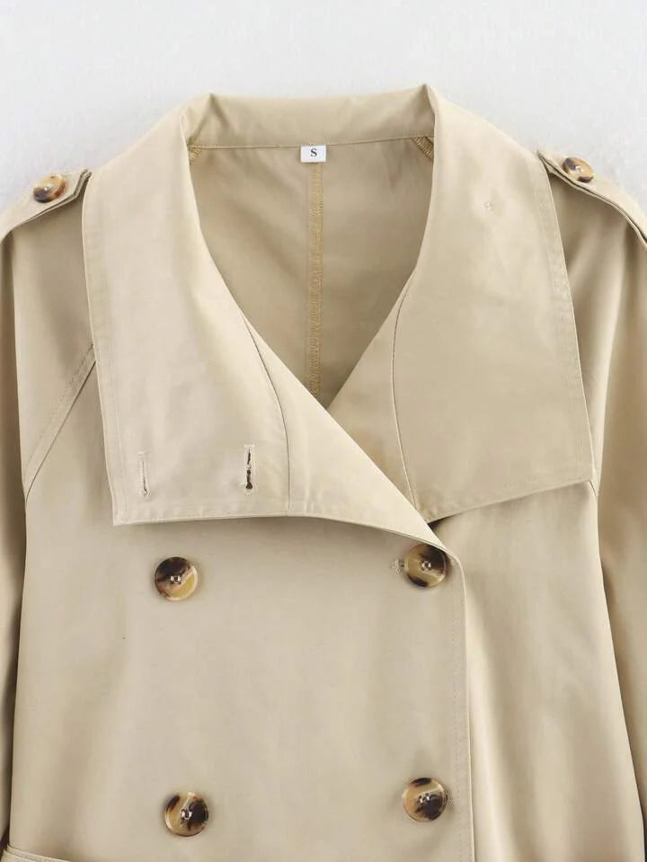 Isabelle high-neck belted trench coat in premium cotton blend with structured stand collar, double-breasted buttons, epaulettes and adjustable cuffs. Tailored silhouette layers over dresses, denim or trousers for refined autumn-winter style.