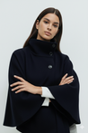 High-neck belted cape jacket in camel wool blend with buttoned collar, cape silhouette and waist-defining tie belt. Soft, warm and comfortable layering piece for autumn and winter, styled over knits or dresses for timeless elegance.