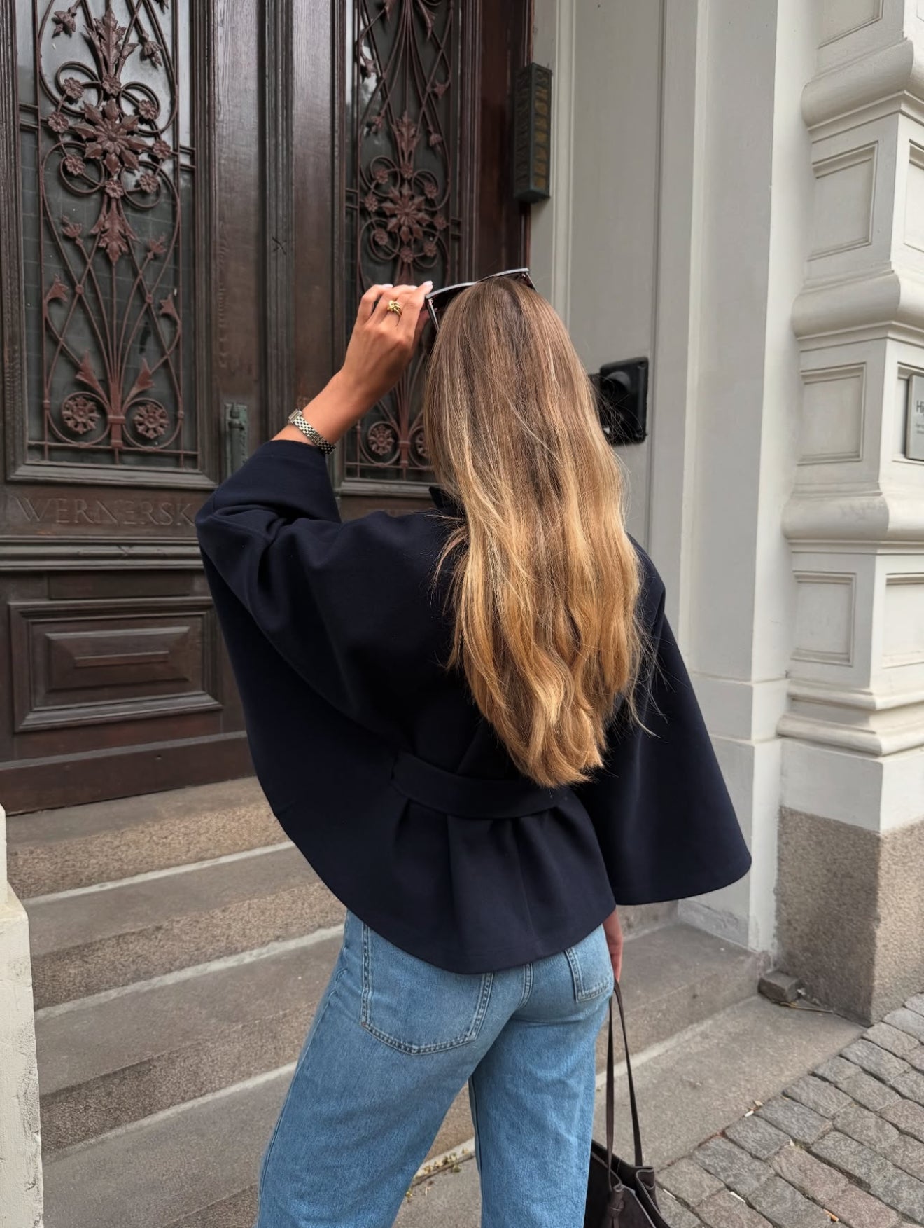 High-neck belted cape jacket in camel wool blend with buttoned collar, cape silhouette and waist-defining tie belt. Soft, warm and comfortable layering piece for autumn and winter, styled over knits or dresses for timeless elegance.