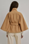 High-neck belted cape jacket in camel wool blend with buttoned collar, cape silhouette and waist-defining tie belt. Soft, warm and comfortable layering piece for autumn and winter, styled over knits or dresses for timeless elegance.