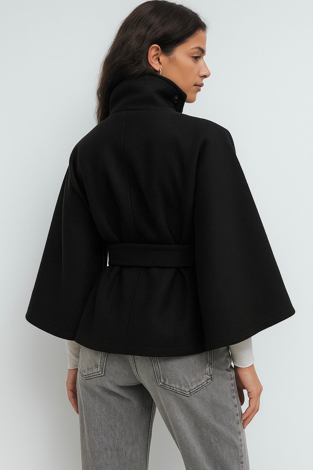 High-neck belted cape jacket in camel wool blend with buttoned collar, cape silhouette and waist-defining tie belt. Soft, warm and comfortable layering piece for autumn and winter, styled over knits or dresses for timeless elegance.