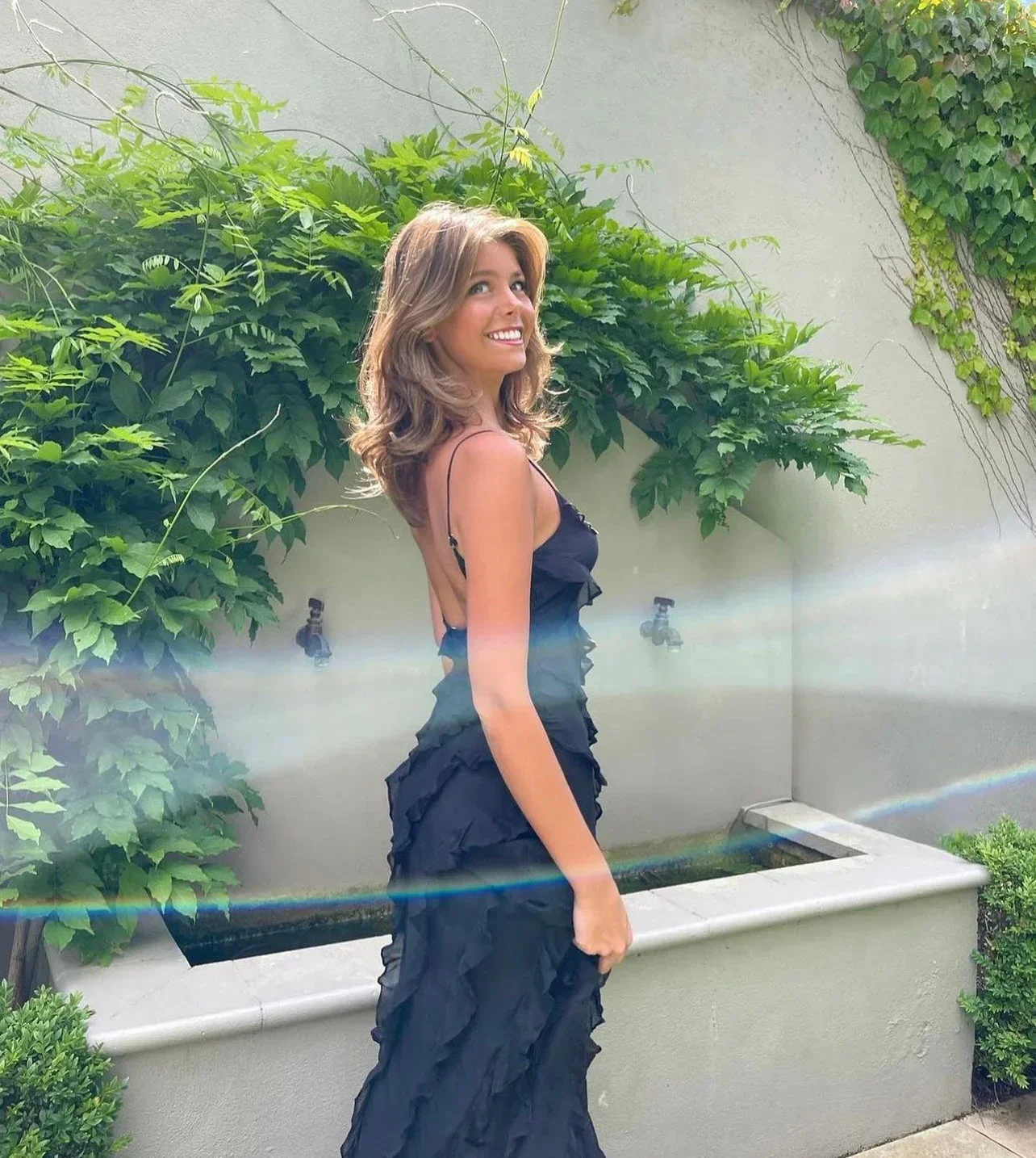 Women’s elegant tulle maxi dress with slender straps, open back and ruched waist. Floaty, ruffled texture and subtle side slit deliver graceful movement. A floor-skimming hem elongates for polished wedding or evening looks.