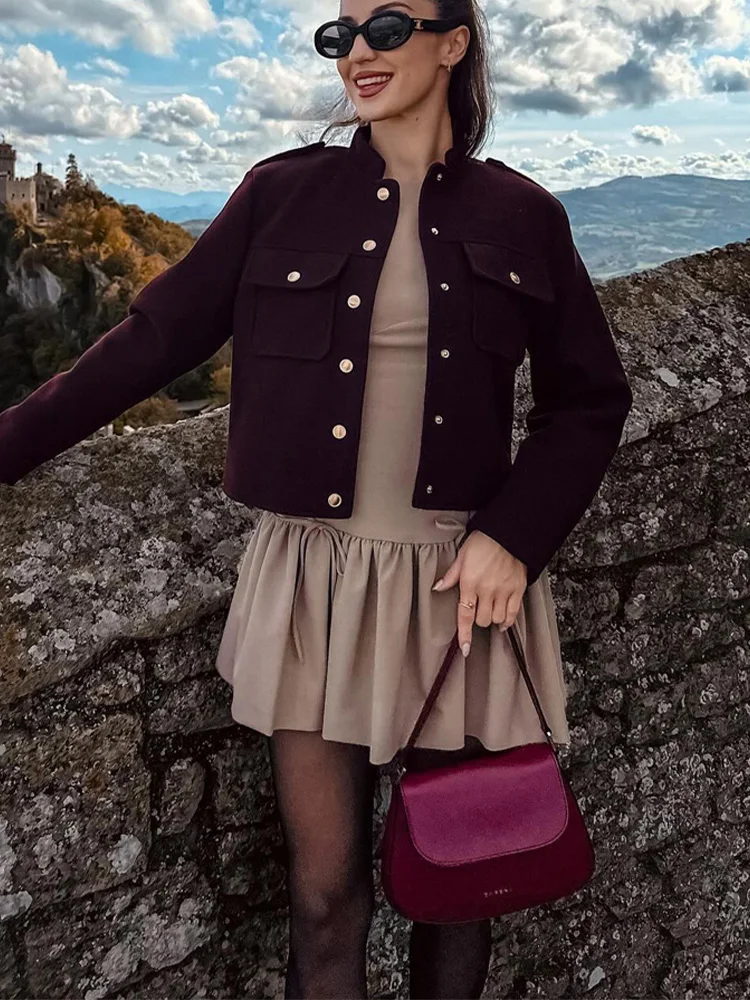 Lilly cropped jacket in deep burgundy featuring statement gold buttons, front flap pockets and a clean, collarless neckline. Soft yet structured woven fabric flatters the waist and layers over dresses, denim or tailoring for refined desk-to-dinner style.