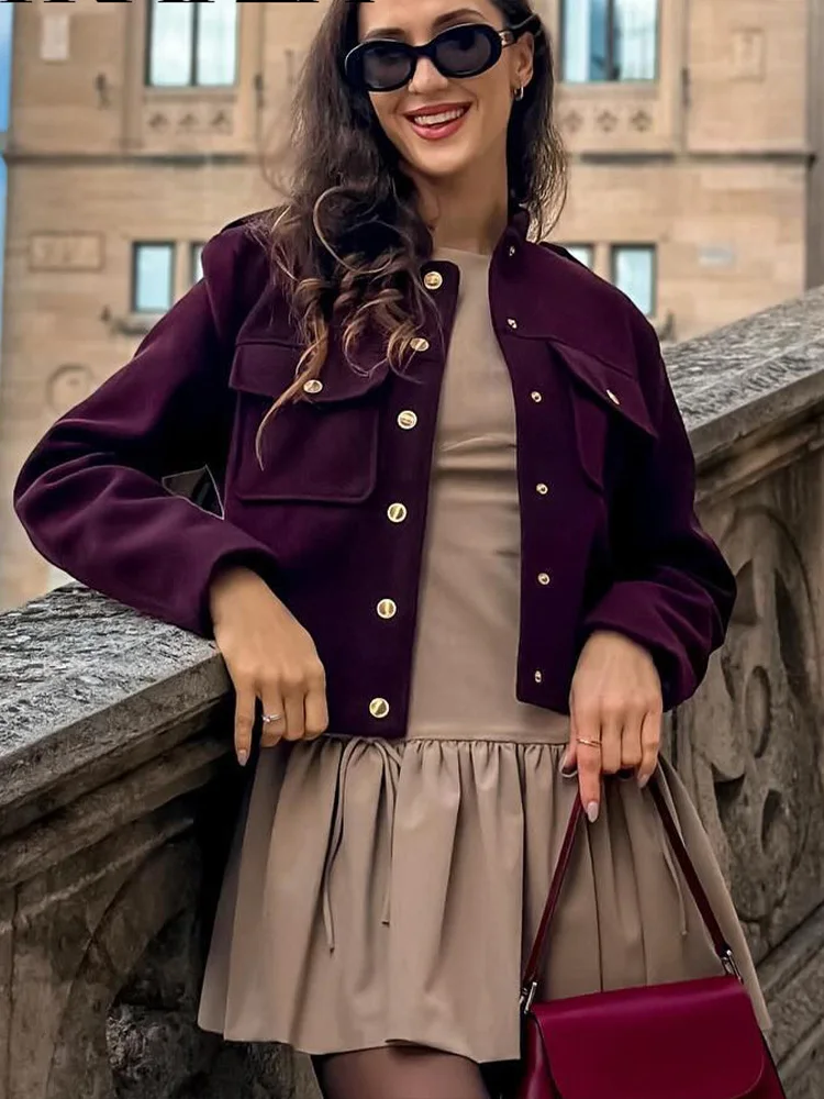 Lilly cropped jacket in deep burgundy featuring statement gold buttons, front flap pockets and a clean, collarless neckline. Soft yet structured woven fabric flatters the waist and layers over dresses, denim or tailoring for refined desk-to-dinner style.