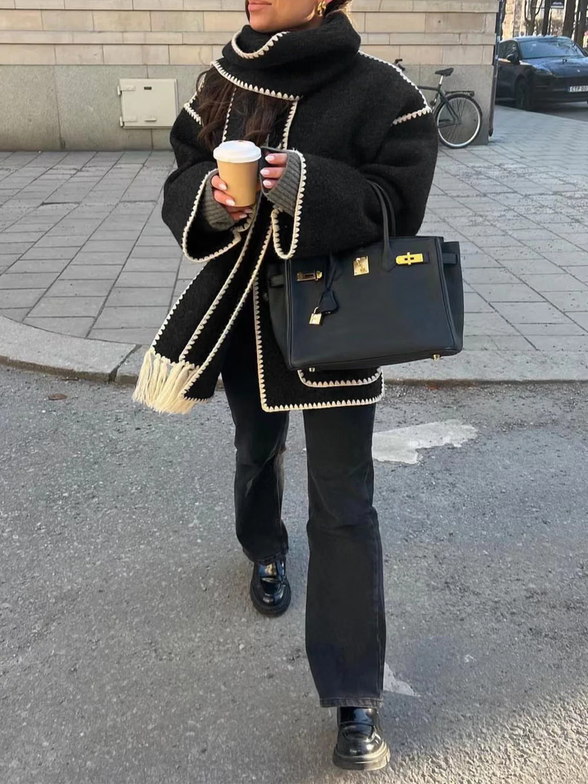 Vintage-inspired jacket in black or grey featuring an integrated scarf with fringe, contrast whipstitch edging, button front and large patch pockets. Relaxed straight silhouette in soft-touch fabric for cozy, stylish layering in cooler weather.