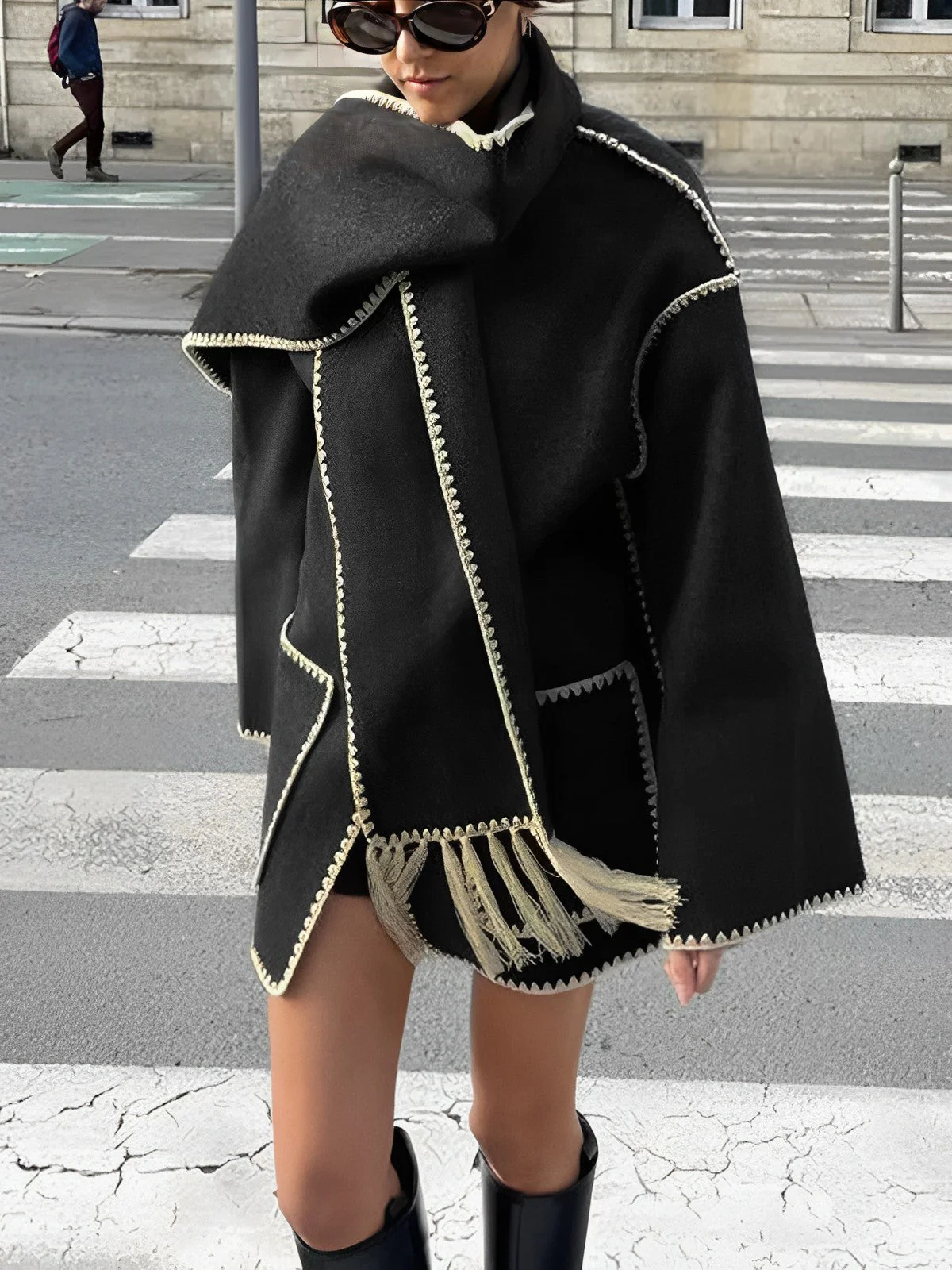 Vintage-inspired jacket in black or grey featuring an integrated scarf with fringe, contrast whipstitch edging, button front and large patch pockets. Relaxed straight silhouette in soft-touch fabric for cozy, stylish layering in cooler weather.