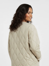 Soft beige quilted oversized jacket featuring wave-pattern stitching, rounded neckline, full front zip and two roomy front pockets. Polyester shell with lightweight fibre fill provides warmth without bulk and a relaxed drape for easy layering in cooler seasons.