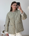 Soft beige quilted oversized jacket featuring wave-pattern stitching, rounded neckline, full front zip and two roomy front pockets. Polyester shell with lightweight fibre fill provides warmth without bulk and a relaxed drape for easy layering in cooler seasons.