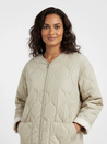 Soft beige quilted oversized jacket featuring wave-pattern stitching, rounded neckline, full front zip and two roomy front pockets. Polyester shell with lightweight fibre fill provides warmth without bulk and a relaxed drape for easy layering in cooler seasons.