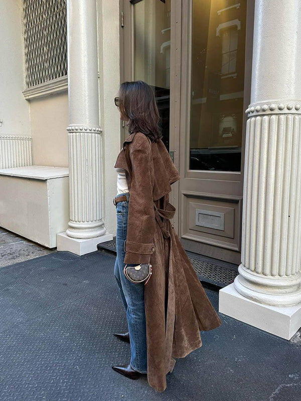 Molly faux suede trenchcoat featuring a velvety-soft finish, relaxed longline silhouette, buttoned front and waist-defining tie belt. Drapes comfortably over knits or dresses, adding refined, feminine style for transitional weather.