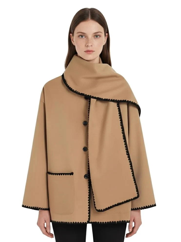 Nellie black wool-blend cape coat featuring a flowing silhouette with white contrast trim, front button fastening, practical side pockets and an attached oversized scarf collar. Warm, elegant outer layer that drapes over denim, knitwear or evening looks.