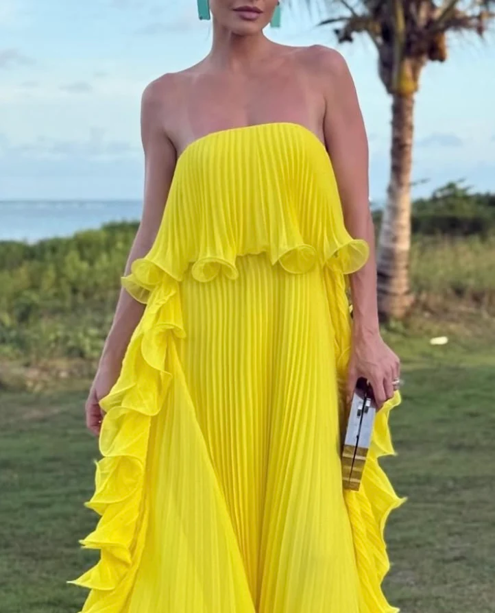 Ravello strapless pleated maxi dress featuring a layered flounce bodice, vertical knife pleats, and cascading side ruffles. Lightweight polyester drape lengthens the silhouette with elegant motion—perfect for weddings, garden parties, and evening events.