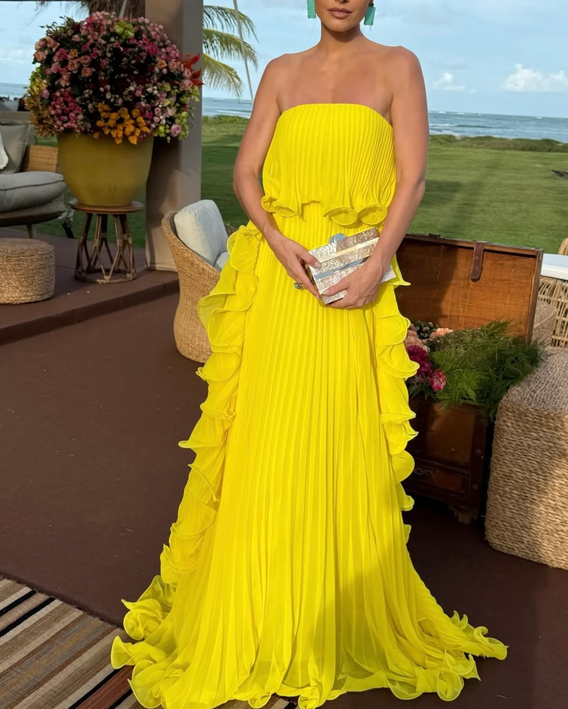 Ravello strapless pleated maxi dress featuring a layered flounce bodice, vertical knife pleats, and cascading side ruffles. Lightweight polyester drape lengthens the silhouette with elegant motion—perfect for weddings, garden parties, and evening events.