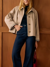 Classic short trench jacket in a warm neutral tone, featuring a pointed collar, button-down closure, minimalist front pockets and a slightly cropped, relaxed silhouette. Soft, structured fabric layers easily over knits or blouses for everyday polish.