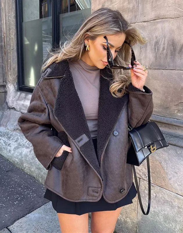 Women’s outerwear jacket in synthetic leather with plush shearling-effect lining, high stand collar and asymmetric button closure. Relaxed silhouette with lined hand pockets for cozy warmth and effortless layering from day to night.