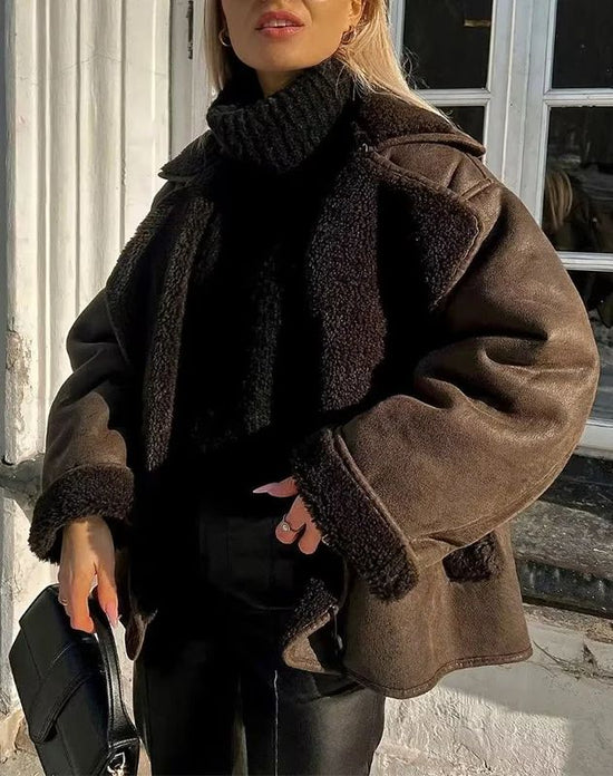 Women’s outerwear jacket in synthetic leather with plush shearling-effect lining, high stand collar and asymmetric button closure. Relaxed silhouette with lined hand pockets for cozy warmth and effortless layering from day to night.