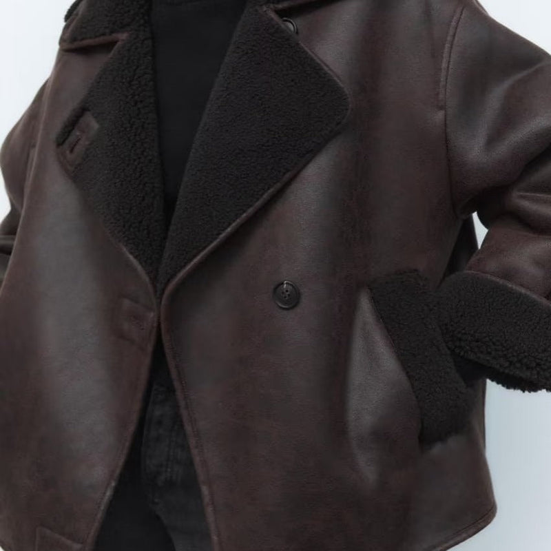 Women’s outerwear jacket in synthetic leather with plush shearling-effect lining, high stand collar and asymmetric button closure. Relaxed silhouette with lined hand pockets for cozy warmth and effortless layering from day to night.