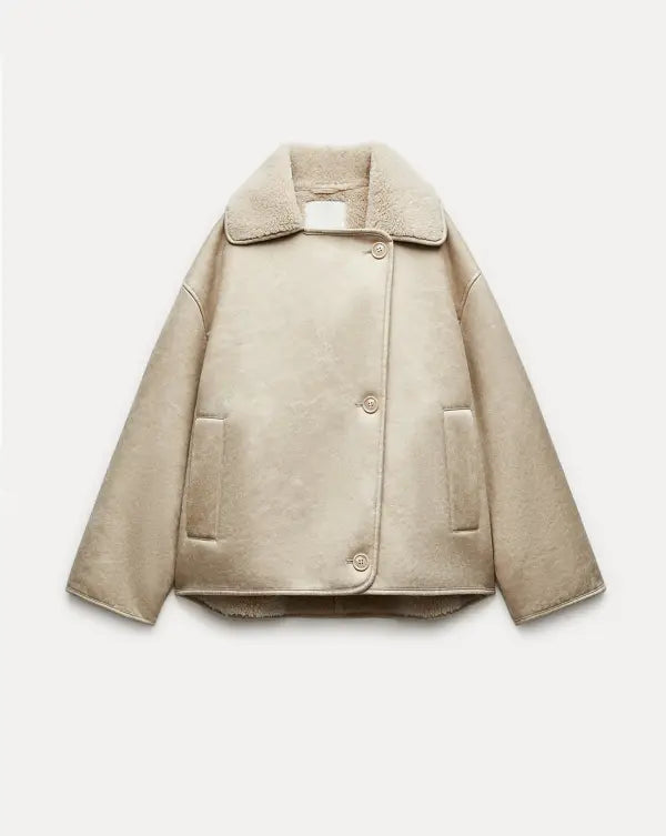 Women’s outerwear jacket in synthetic leather with plush shearling-effect lining, high stand collar and asymmetric button closure. Relaxed silhouette with lined hand pockets for cozy warmth and effortless layering from day to night.
